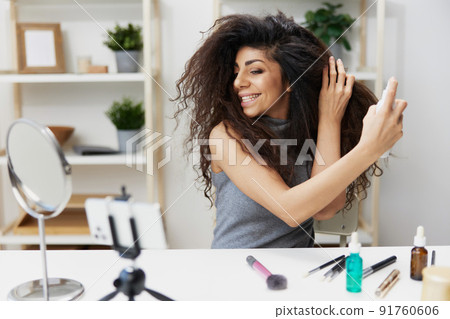 Happy tanned handsome curly Latin beauty blogger in casual top tells about thermal protection in home interior. Copy space Mockup Banner. Influencer record video review blog using smartphone Happy tanned handsome curly Latin beauty blogger in casual top tells about thermal protection in home interior. Copy space Mockup Banner. Influencer record video review blog using smartphone 91760606