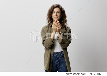Excited shocked happy funny curly beautiful woman in casual khaki green shirt hold apple looks at camera posing isolated on over white background. Natural Eco-friendly products concept. Copy space Excited shocked happy funny curly beautiful woman in casual khaki green shirt hold apple looks at camera posing isolated on over white background. Natural Eco-friendly products concept. Copy space 91760613