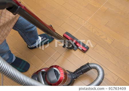 [Middle housewife cleaning flooring with a cyclone cleaner] 91763409