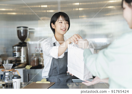 Female staff handing over cafe products 91765424