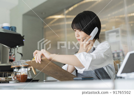 Female staff making a phone call to the cafe Female staff making a phone call to the cafe 91765502