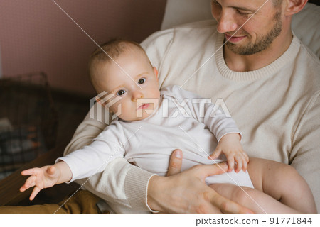 A Caucasian father holds his baby son in his arms. Happy fatherhood and family A Caucasian father holds his baby son in his arms. Happy fatherhood and family 91771844