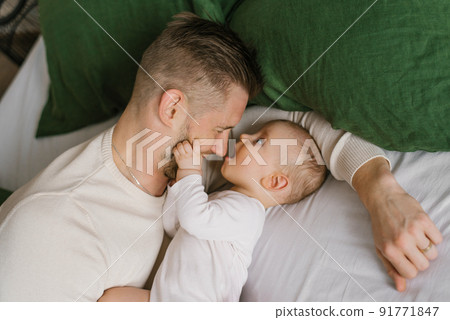 Father and son baby are lying on the bed and having fun Father and son baby are lying on the bed and having fun 91771847
