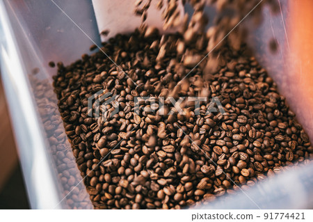 Roasted coffee beans from roaster machine pouring into the special box for selling Roasted coffee beans from roaster machine pouring into the special box for selling 91774421