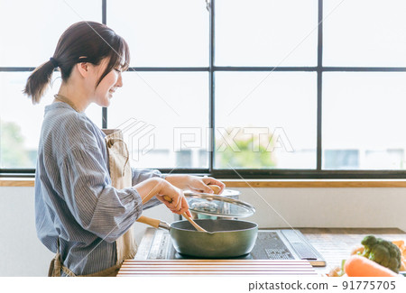 A woman using a frying pan in the kitchen 91775705
