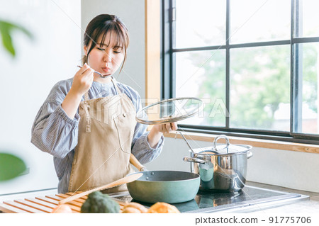 A woman tasting food in the kitchen 91775706