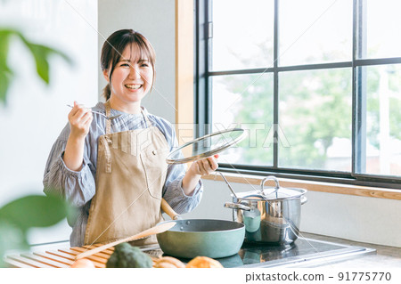 A woman tasting food in the kitchen 91775770