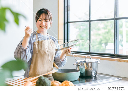 A woman tasting food in the kitchen 91775771