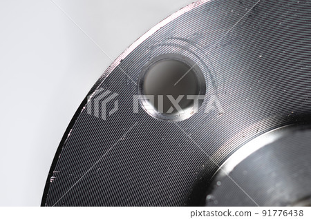 Close-up of a hole in a metal flange against a gray background. Production equipment Close-up of a hole in a metal flange against a gray background. Production equipment 91776438