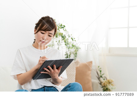 A woman (creator) who uses a tablet at home 91777089