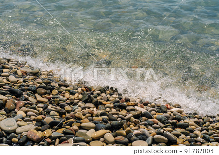 Bank of pebbles with the sea and beach in the background. 91782003