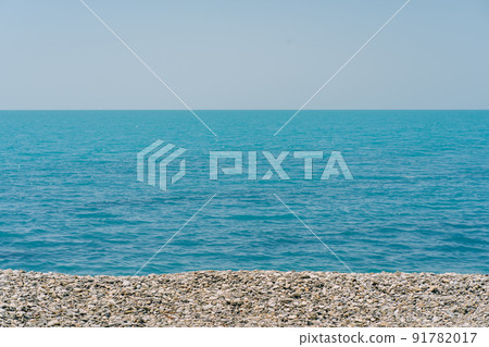 Bank of pebbles with the sea and beach in the background. 91782017