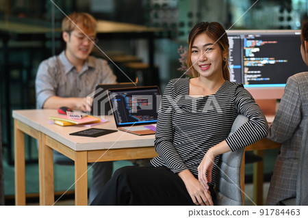 Confident young female professionals web developer sitting in software development office 91784463
