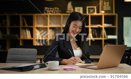 Beautiful millennial female entrepreneur working with financial reports in contemporary office 91784566