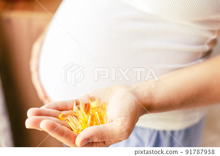 Healthcare, treatment, supplements. Happy smiling woman taking pill with supplement vitamin Omega 3. Pregnancy, medicine health care concept. Healthcare, treatment, supplements. Happy smiling woman taking pill with supplement vitamin Omega 3. Pregnancy, medicine health care concept. 91787938