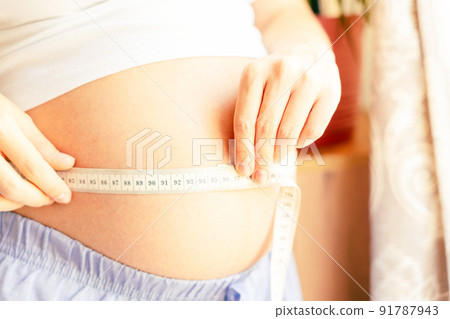 Pregnant belly woman measure. Happy beautiful pregnant woman with tape measuring belly. Pregnancy, medicine health care concept. 91787943