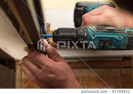 Drilling and installation of interior doors, the craftsman makes a hole in the door frame with a hand drill. 91789922