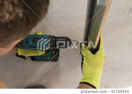 Drilling a hole in the door with a green screwdriver, close-up of the drilling process, Drilling a hole in the door with a green screwdriver, close-up of the drilling process, 91789930