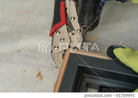 The craftsman drills the door for connection at the corner, the clamps hold the two slats of the door. 91789943