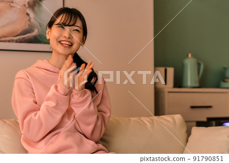 一個年輕女子晚上看電視的掌聲 91790851