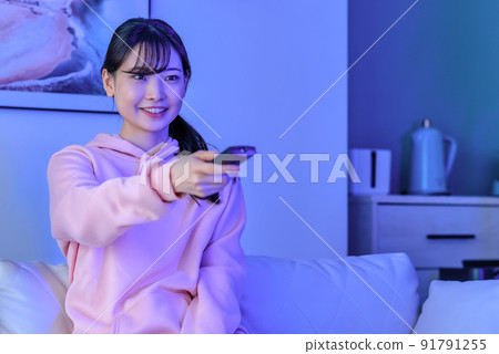 一個在午夜看電視的年輕女子微笑著 91791255