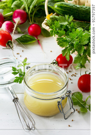 Homemade salad dressing vinaigrette with mustard, olive oil, lemon juice and various fresh vegetables and herbs on a wooden background. The concept of a healthy diet and detox diet. 91797397