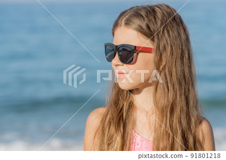 Close-up portrait of a girl in a bathing suit and glasses. 91801218