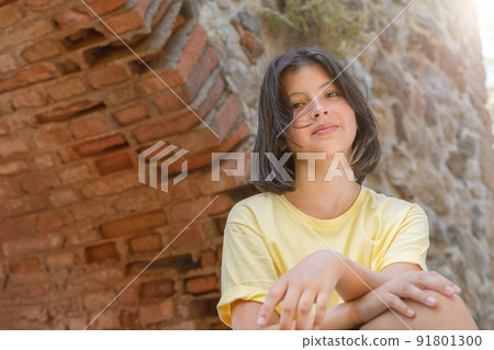 Portrait of a young girl on the background of a stone wall with an arch. Portrait of a young girl on the background of a stone wall with an arch. 91801300