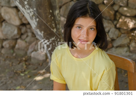 A pretty young girl poses for the camera on the background of a stone wall. A pretty young girl poses for the camera on the background of a stone wall. 91801301