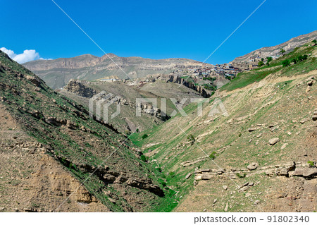 mountain landscape with rocky cliffs, in the distance the mountain village of Chokh in Dagestan 91802340