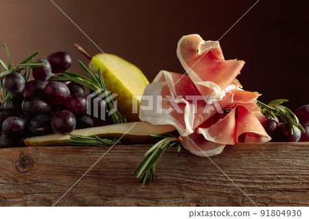 Prosciutto with rosemary, pear, and grapes. 91804930