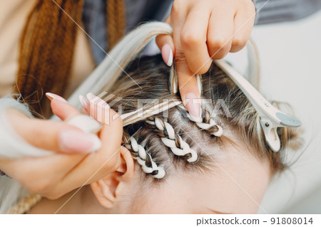 Hairstylist braided afro braids dreadlocks kanekalon pigtails hair of female client in barber salon. Hairstylist braided afro braids dreadlocks kanekalon pigtails hair of female client in barber salon. 91808014