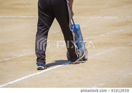 The feet of the teacher who draws a white line on the playground 91812639