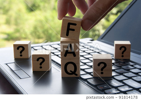 Hand holding FAQ word on wooden block on top of laptop with blurred nature background. Information concept 91814178