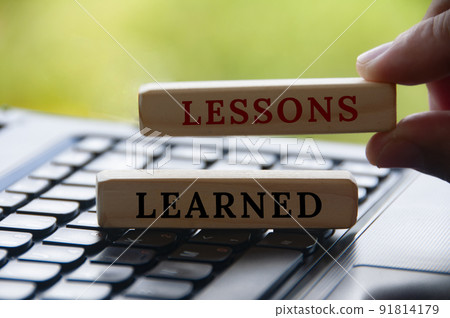 Hand holding lessons learned text on wooden blocks on top of a laptop with blurred nature background. Learning concept Hand holding lessons learned text on wooden blocks on top of a laptop with blurred nature background. Learning concept 91814179