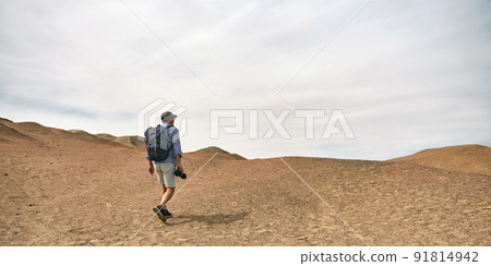 asian male backpacker landscape photographer walking on a hill looking at view, rear view 91814942