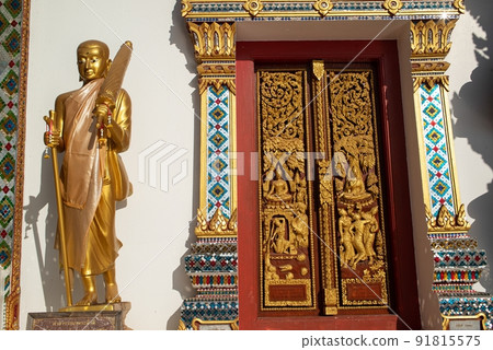 Gold Phra Sivali or Phra Sivalee Buddhist Monk Statue standing front of Thai Church in Wat Phra That Choeng Chum Worawihan It is an important sacred place of the Thailand. 91815575