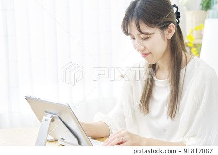 A woman using a tablet in the living room A woman using a tablet in the living room 91817087