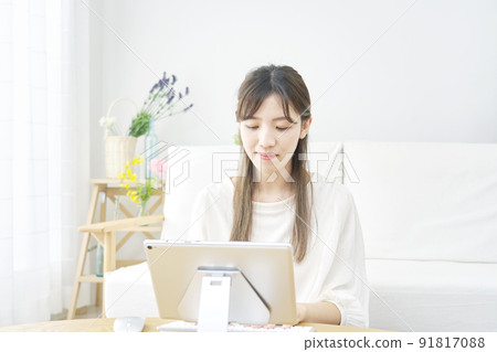 A woman using a tablet in the living room A woman using a tablet in the living room 91817088