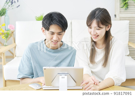 一對夫婦在客廳裡看平板電腦 91817091