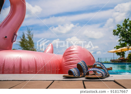 Vacation and leisure summer lifestyle by takeoff shoe laying beside pink flamingo beside th swimming pool at summer period. 91817667