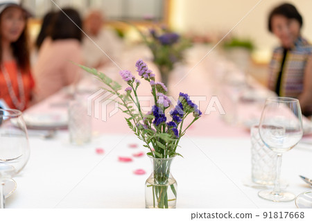 flowers decorate on the dinning long table in the luxury relax event with the blur social people behind 91817668