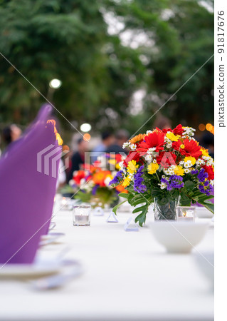 red yellow purple and white flowers is set on the long white cover table and ready for luxury dinner in the garden field. 91817676
