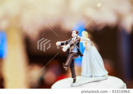 groom doll and statue is running away but bride can catch him finally. the funny wedding story doll on the top of cake. groom doll and statue is running away but bride can catch him finally. the funny wedding story doll on the top of cake. 91818968