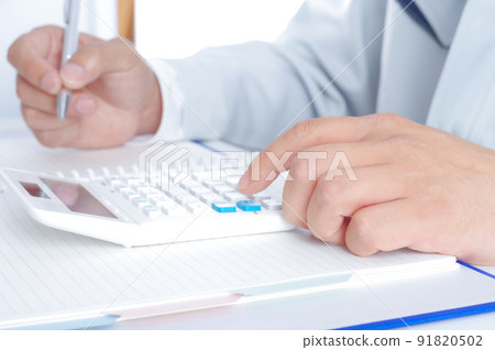 A man in work clothes doing calculations with a calculator 91820502