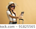 Young Asian girl dress in white shirt and jeans ready to travel on vacation on yellow isolated background 91825565