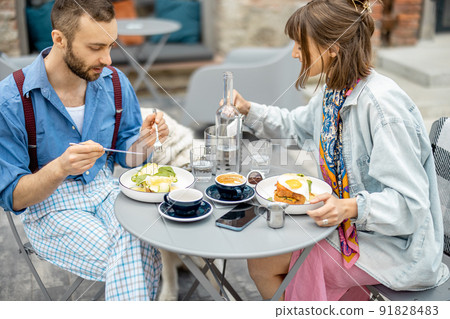 Stylish man and woman have delicious breakfast at cafe outdoors 91828483