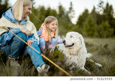 Mother with daughter and dog sit on nature 91829393