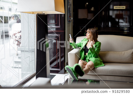 Busienss woman with phone at hotel lobby Busienss woman with phone at hotel lobby 91829580