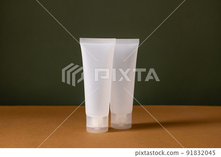 A set of empty white tube bottles with cosmetics on brown and green background . Eco-friendly cosmetics. The concept of cosmetic skin and body care, treatment, youth preservation. A set of empty white tube bottles with cosmetics on brown and green background . Eco-friendly cosmetics. The concept of cosmetic skin and body care, treatment, youth preservation. 91832045